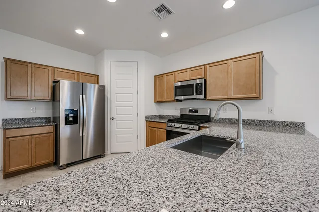 a kitchen with stainless steel appliances granite countertop a refrigerator a stove a sink a microwave a sink and dishwasher