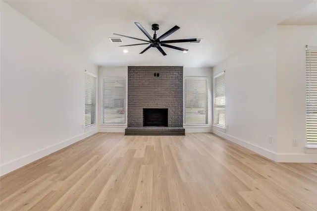 a view of a livingroom with a ceiling fan a fireplace and wooden floor