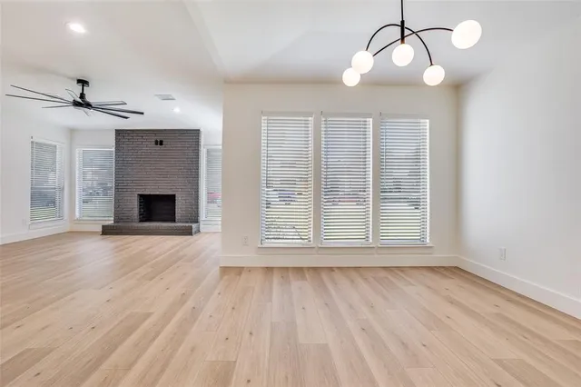a view of an empty room with wooden floor fireplace and a window
