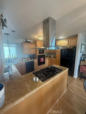 a kitchen with kitchen island a stove a refrigerator a sink a dining table and chairs with wooden floor