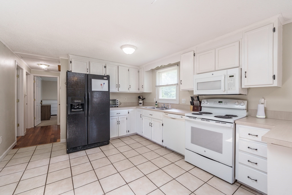 75 Puritan Road Springfield, MA 01119 - Photo 8 of 33 a kitchen with white cabinets a refrigerator stove and sink