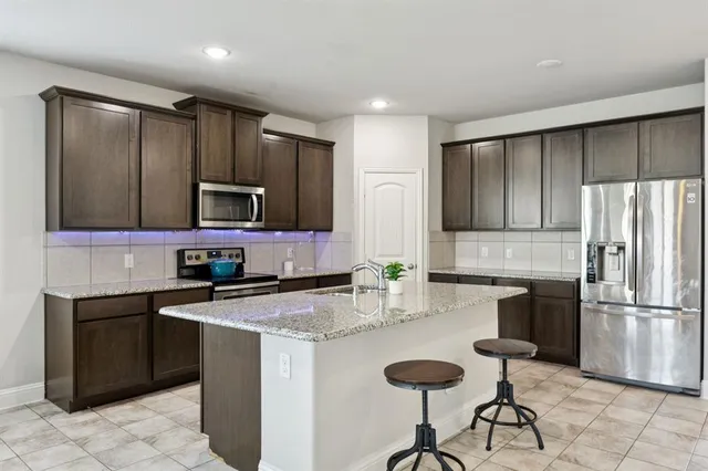 a kitchen with granite countertop a sink stainless steel appliances and cabinets