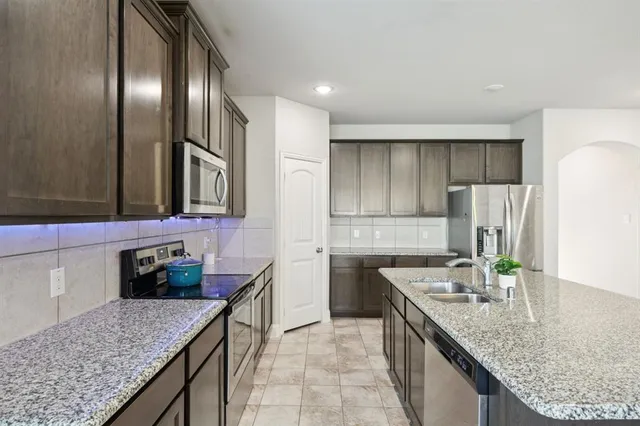 a kitchen with stainless steel appliances granite countertop a sink and a refrigerator