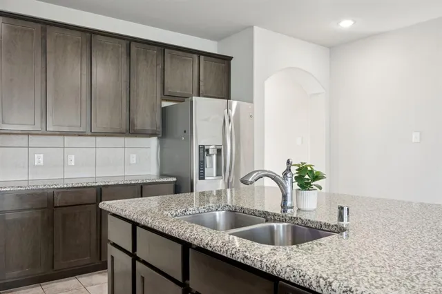 a kitchen with granite countertop a sink a refrigerator and cabinets