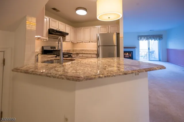a view of a kitchen with kitchen island a sink stove and refrigerator