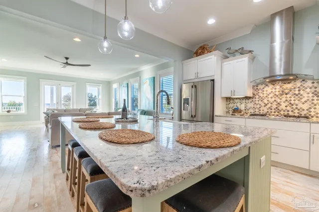 a kitchen with granite countertop kitchen island stainless steel appliances sink stove and white cabinets