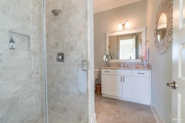 a bathroom with a granite countertop sink a mirror and shower