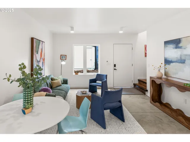 a living room with furniture a potted plant and kitchen view