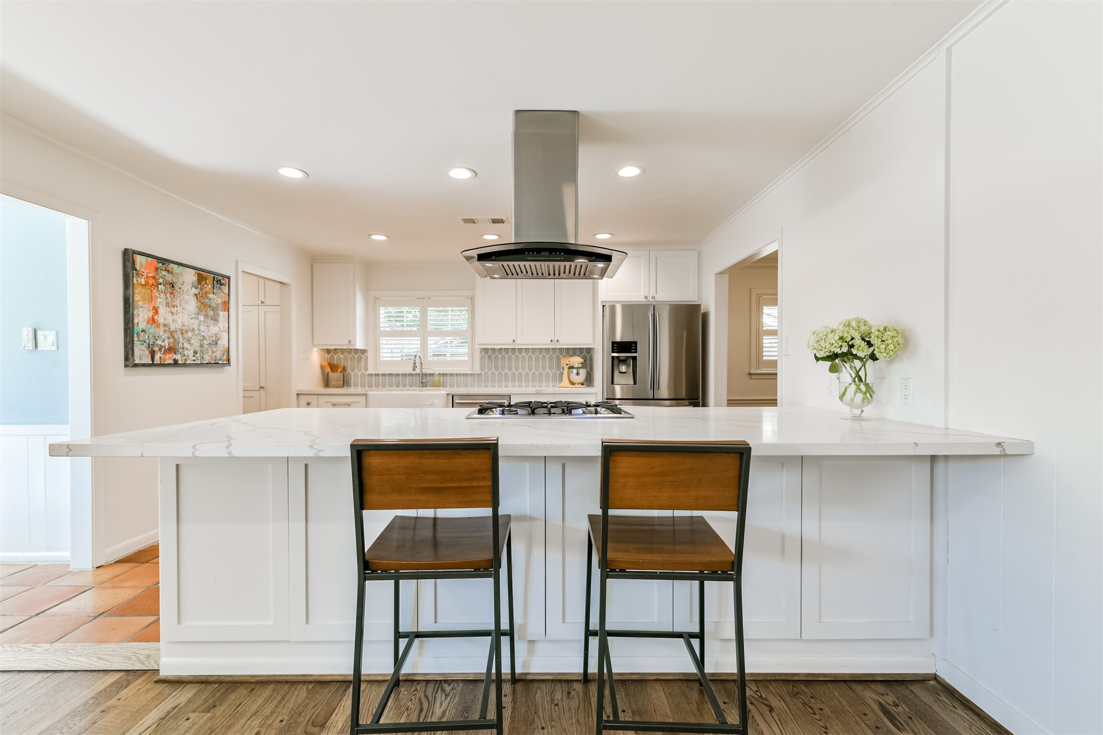 7819 Fairdale Lane Houston, TX 77063 - Photo 8 of 34 Dreamy chef's kitchen, remodeled in 2021, features shaker cabinetry, beautiful quartz countertops, a decorative backsplash and a large breakfast bar with storage underneath.