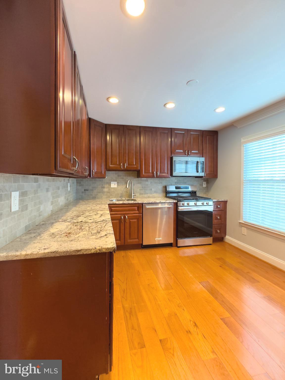 2419 Ansdel Court Reston, VA 20191 - Photo 16 of 41 a kitchen with granite countertop wooden cabinets and stainless steel appliances