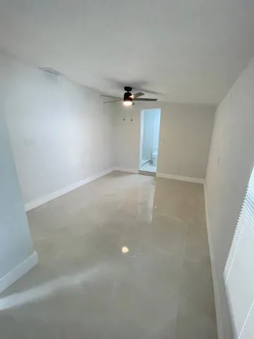 an empty room with a ceiling fan and carpet