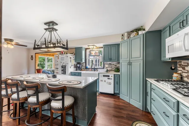 a kitchen with sink a refrigerator and chairs