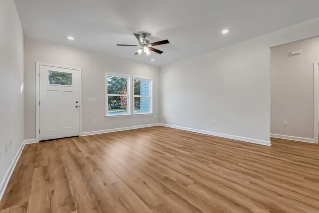 a view of empty room with wooden floor and fan