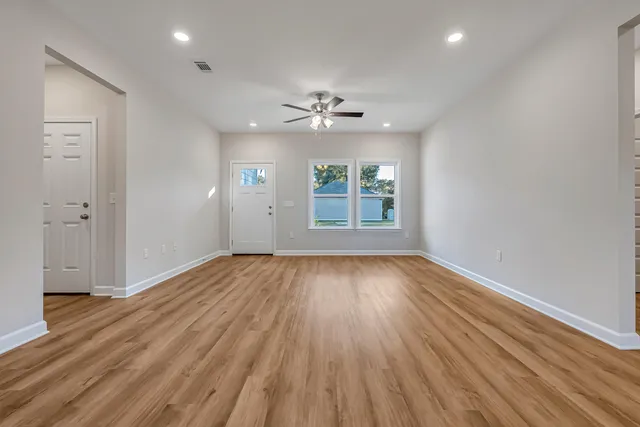 an empty room with wooden floor and windows