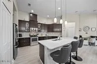 a kitchen with stainless steel appliances kitchen island granite countertop a sink a stove a microwave a refrigerator and chairs