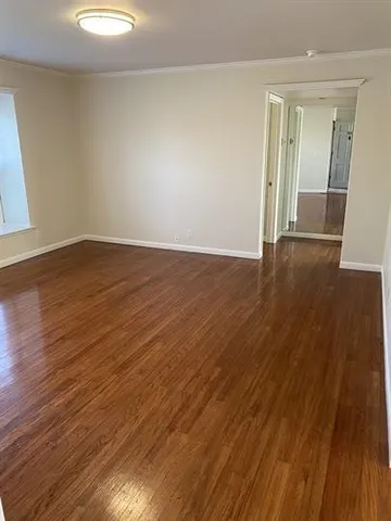 an empty room with wooden floor and mirror