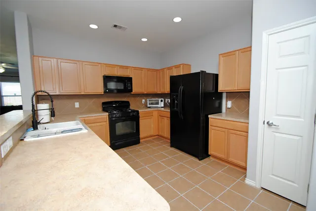 a kitchen with stainless steel appliances granite countertop a refrigerator a stove a sink and a microwave