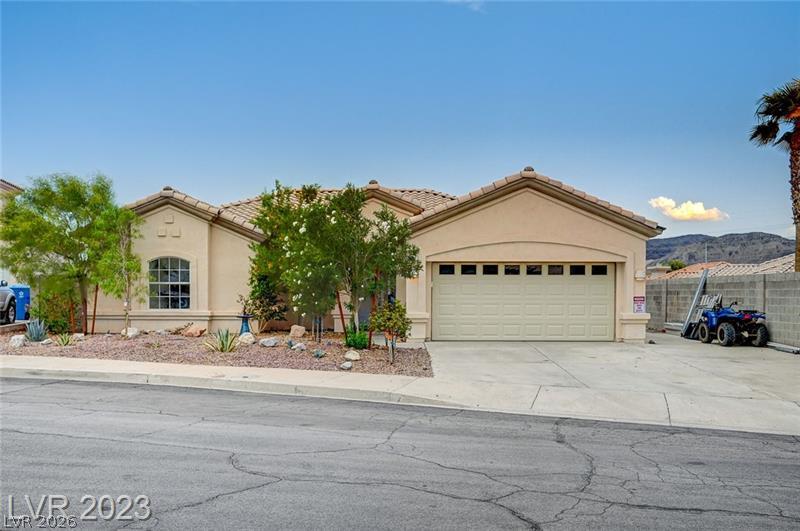 A well-maintained facade with mature desert landscaping and an integrated garage presents a charming welcome.