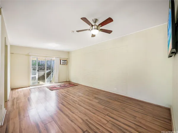 a view of empty room with wooden floor and fan