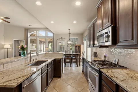 a kitchen with granite countertop a sink stainless steel appliances and lots of counter space