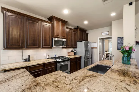 a kitchen with stainless steel appliances granite countertop a refrigerator a stove a sink and a microwave