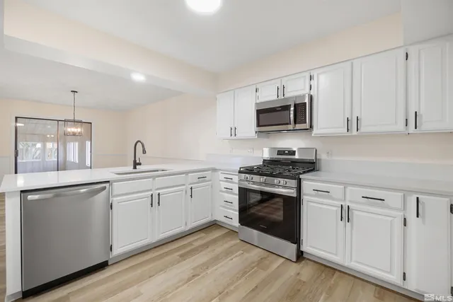 a kitchen with granite countertop white cabinets and stainless steel appliances
