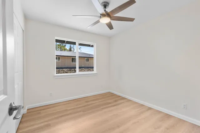 an empty room with a window and ceiling fan