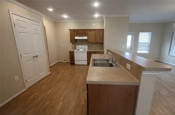 a view of a kitchen with kitchen island a sink wooden floor and a counter top space