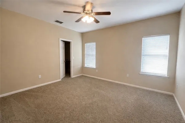 an empty room with windows and fan