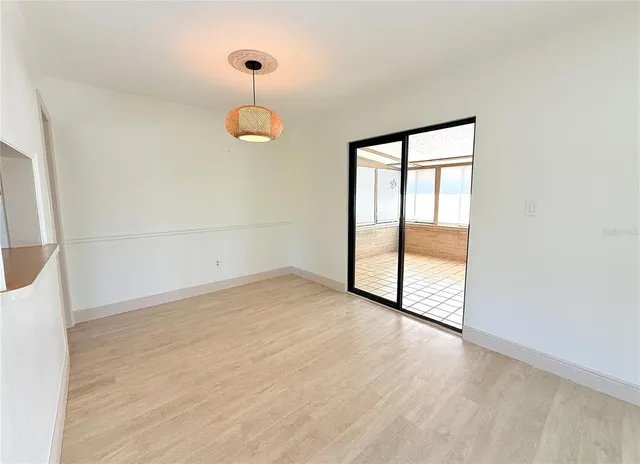 a view of an empty room with wooden floor and windows