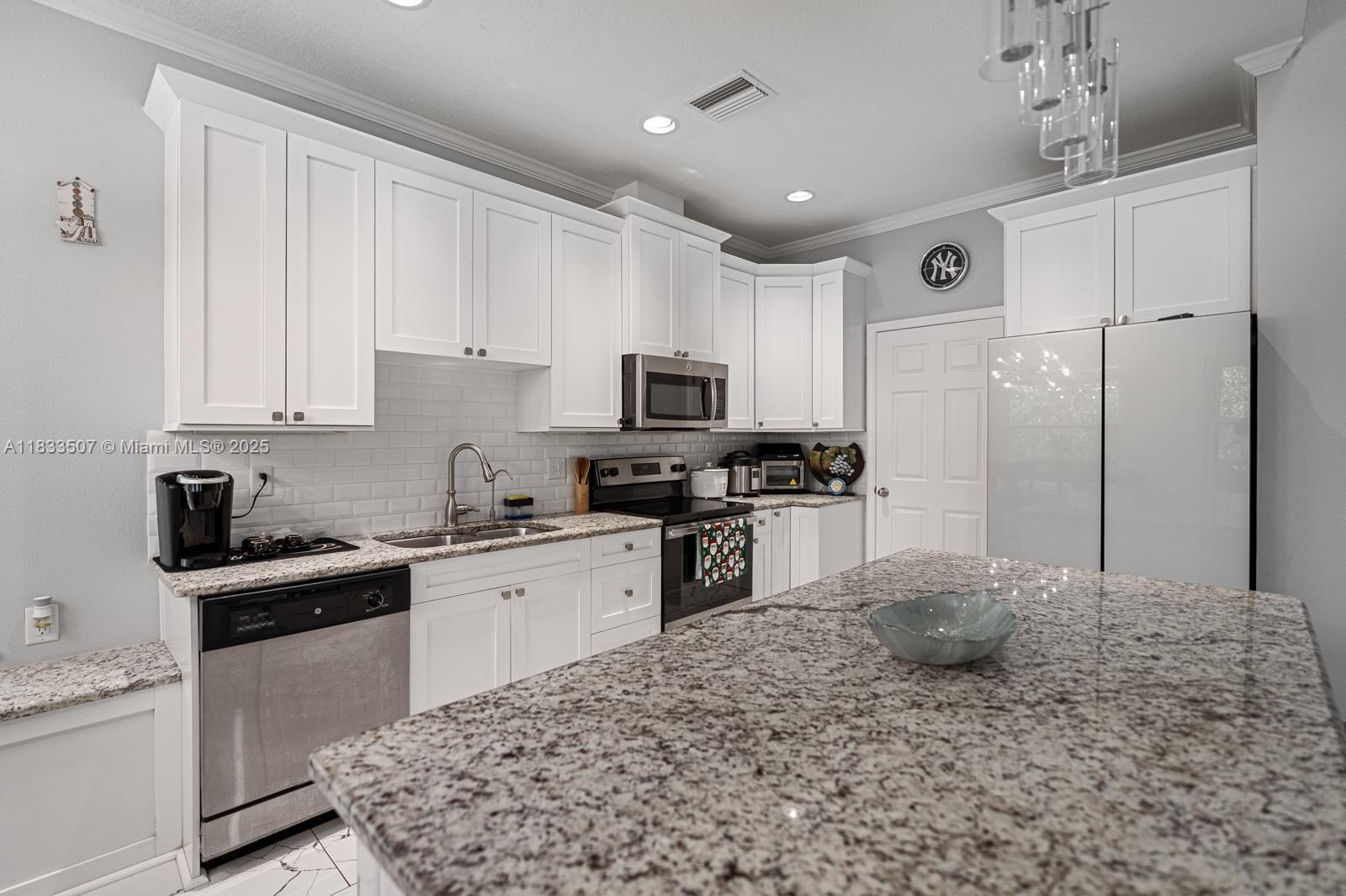4836 Troydale Road Tampa, FL 33615 - Photo 18 of 52 a kitchen with granite countertop a sink stainless steel appliances and white cabinets