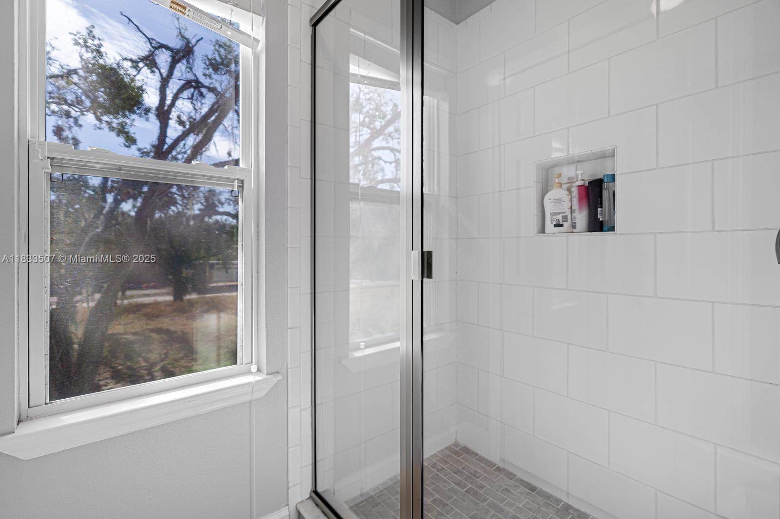4836 Troydale Road Tampa, FL 33615 - Photo 22 of 52 a bathroom with a painting on the wall and a glass door