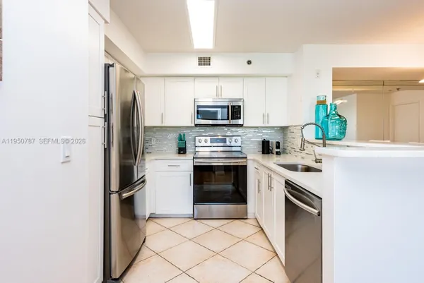 a kitchen with stainless steel appliances a sink stove refrigerator and cabinets
