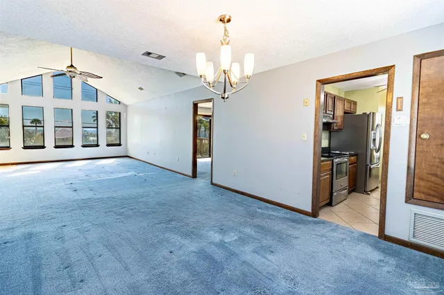 a view of a big room with a chandelier fan and windows