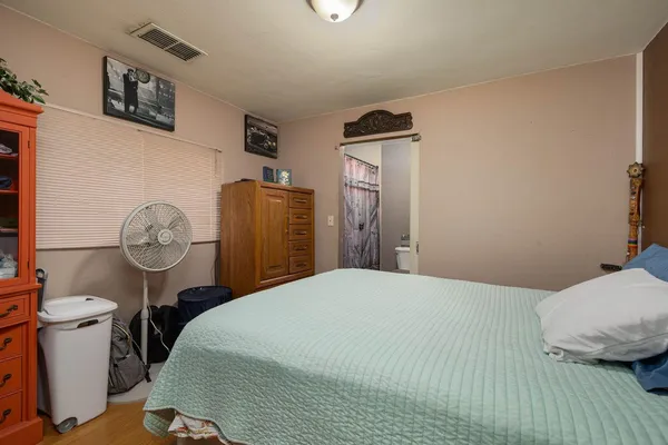 a bedroom with a bed and a lamp on dresser