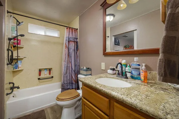 a bathroom with a granite countertop toilet sink and mirror