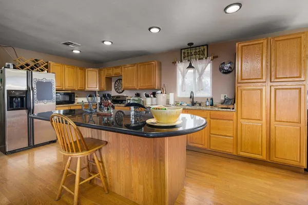 a kitchen with stainless steel appliances granite countertop a sink a stove and a table with chairs