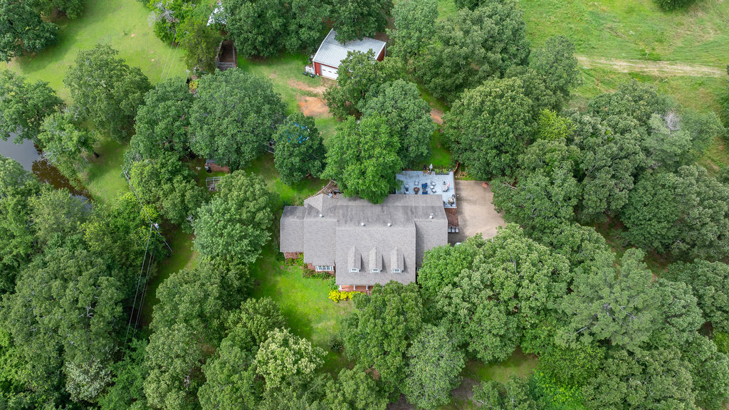 365 Calihan Road Booneville, AR 72927 - Photo 21 of 59 Expansive property featuring a residence with a gray shingle roof, multiple dormer windows, a gravel driveway, and a paved patio area