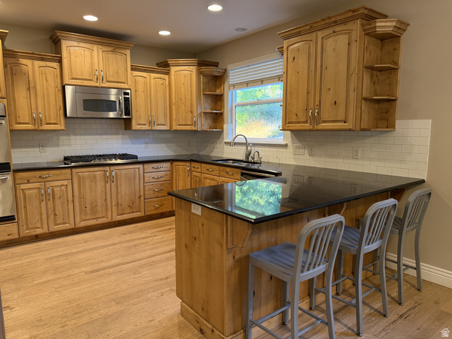 2388 East 850 South Springville, UT 84663 - Photo 13 of 24 Chef's kitchen featuring warm wood cabinetry, black granite countertops, stainless steel appliances, subway tile backsplash, and a large center island with seating for three