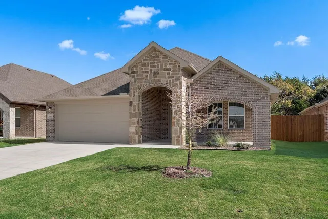 a front view of a house with a garden and yard