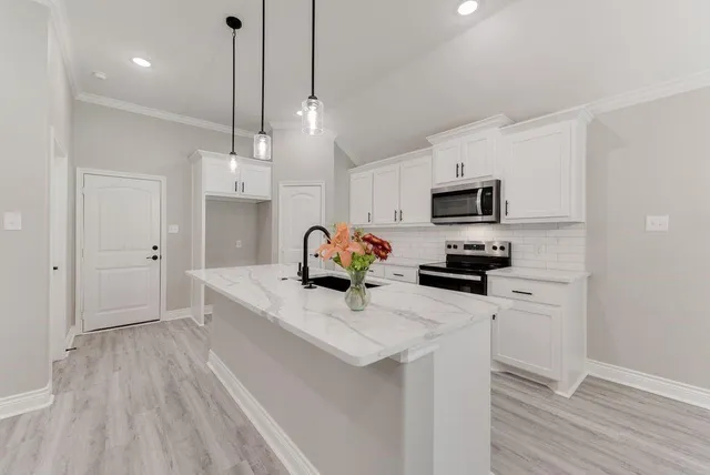 a kitchen with stainless steel appliances a white center island a stove a refrigerator cabinets and a wooden floor