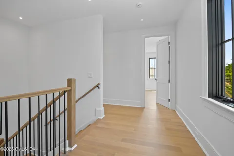 a view of a hallway with wooden floor and stairs