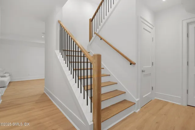 a view of staircase with wooden floor and white walls