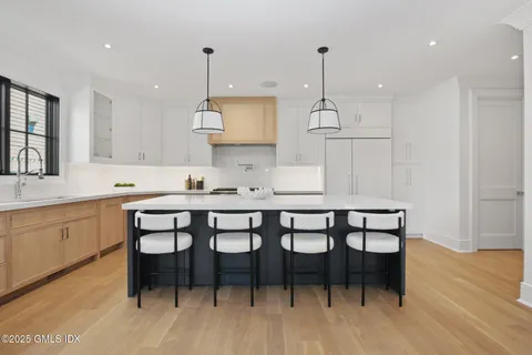 a kitchen with granite countertop a dining table chairs and white cabinets