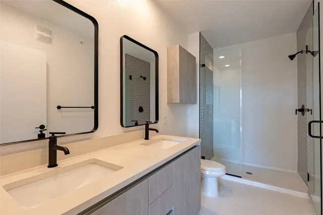 a bathroom with a sink double vanity mirror and a toilet