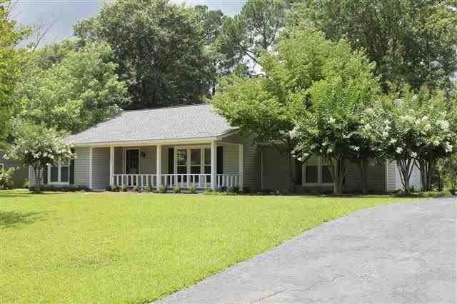 a front view of a house with a yard and trees
