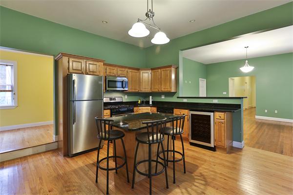 a kitchen with stainless steel appliances granite countertop a refrigerator a stove a sink dishwasher and a dining table with wooden floor