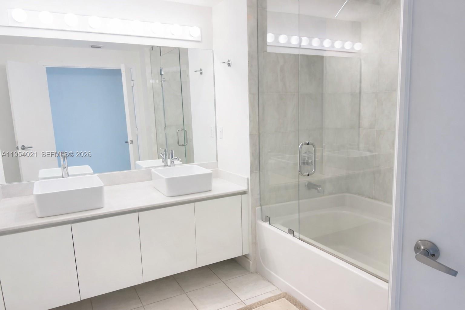 601 Northeast 36th Street, Unit 1112 Miami, FL 33137 - Photo 8 of 32 a bathroom with a bathtub a shower a sink and a mirror