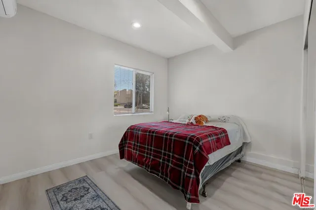 a bed sitting in a bedroom next to a lamp with wooden floor