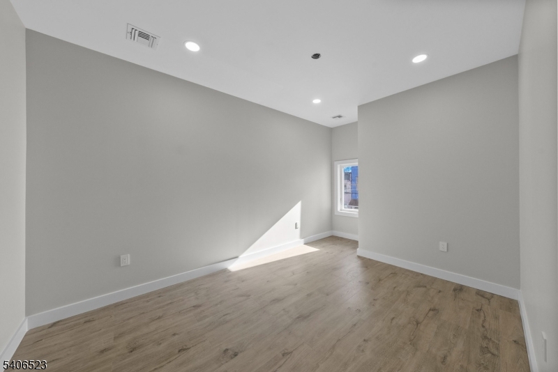 404 Washington Street Perth Amboy, NJ 08861 - Photo 17 of 45 an empty room with wooden floor and windows